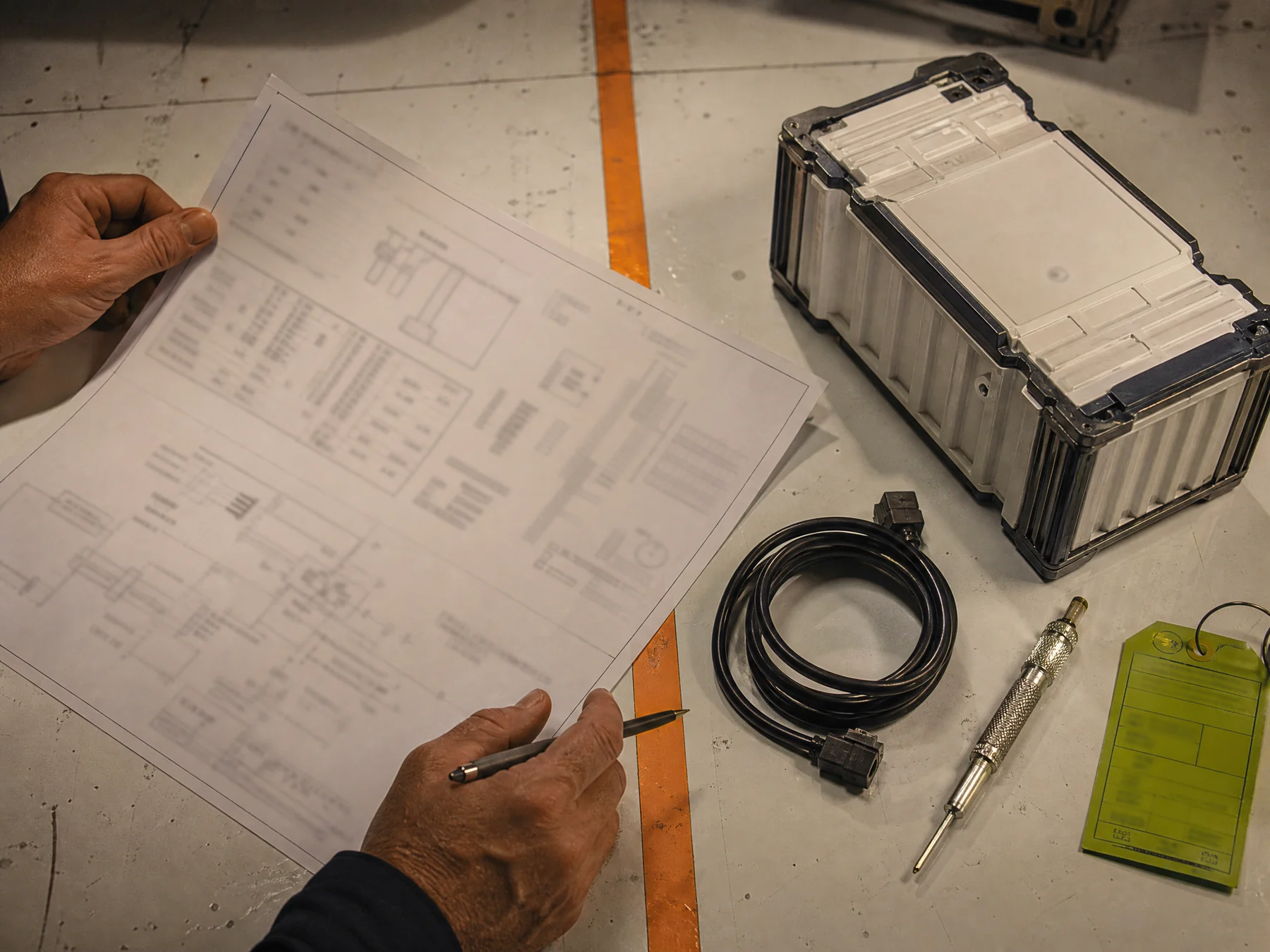 Schema printout, storage module and cable on a technical table